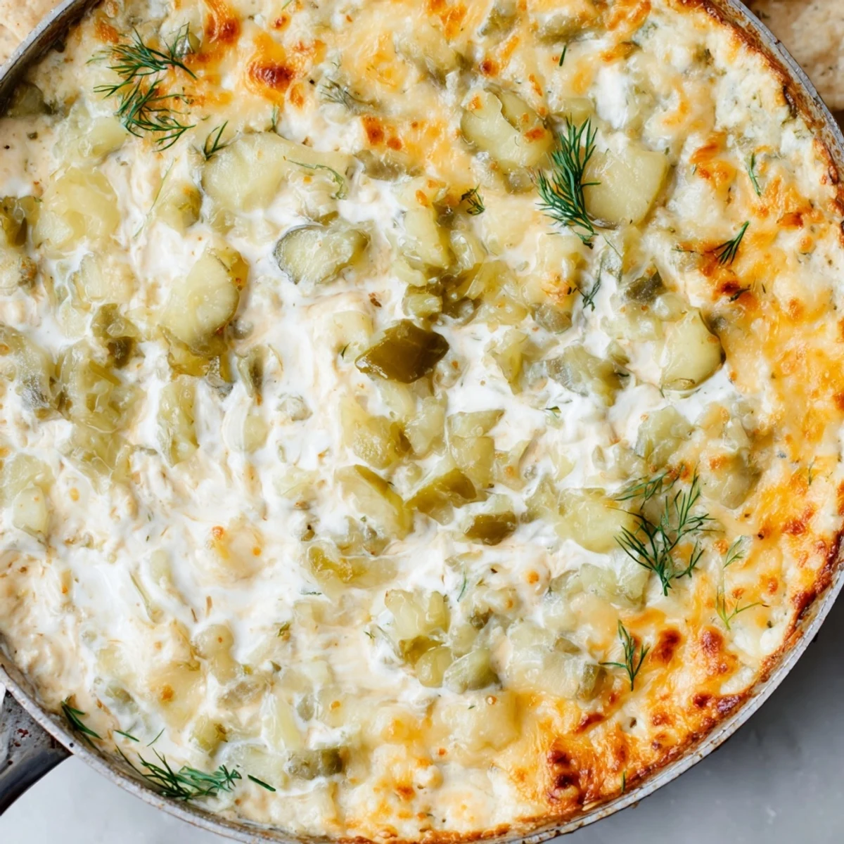Creamy Dill Pickle Queso Fundido Dip bubbling, served hot with crispy tortilla chips.