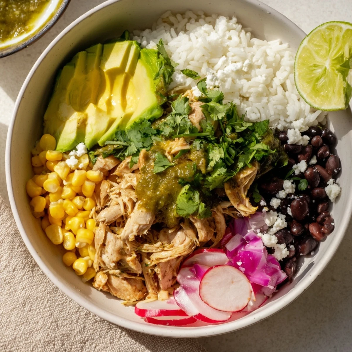 A colorful Green Enchiladas Rice Bowl topped with fresh avocado and cheese.  