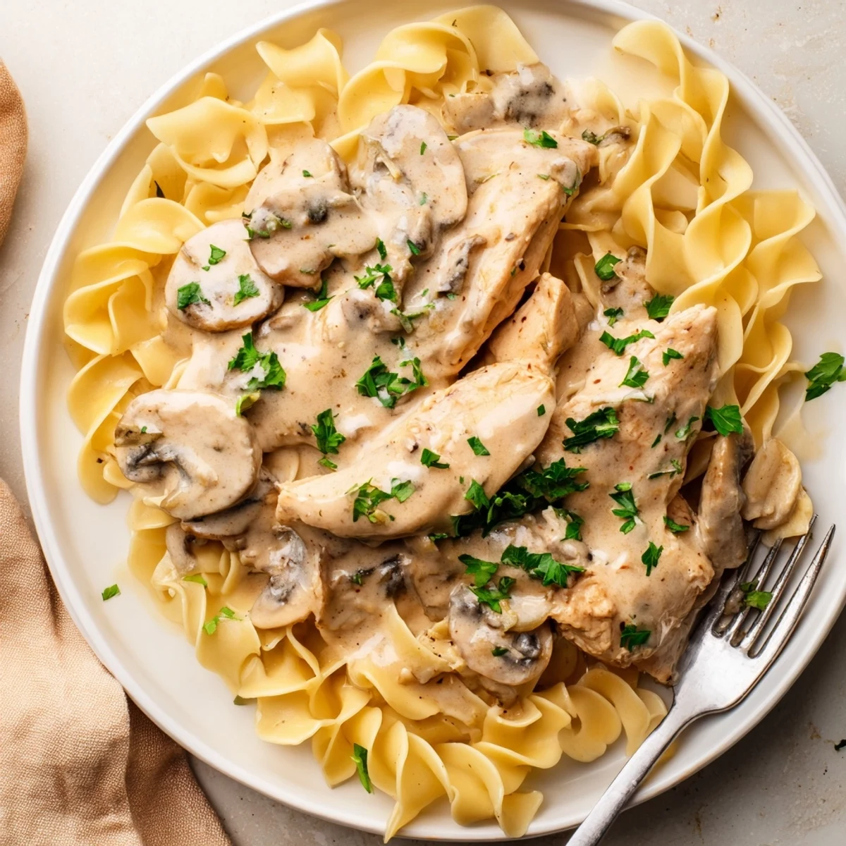 Creamy Chicken Stroganoff served over egg noodles, topped with fresh parsley and mushrooms.  
