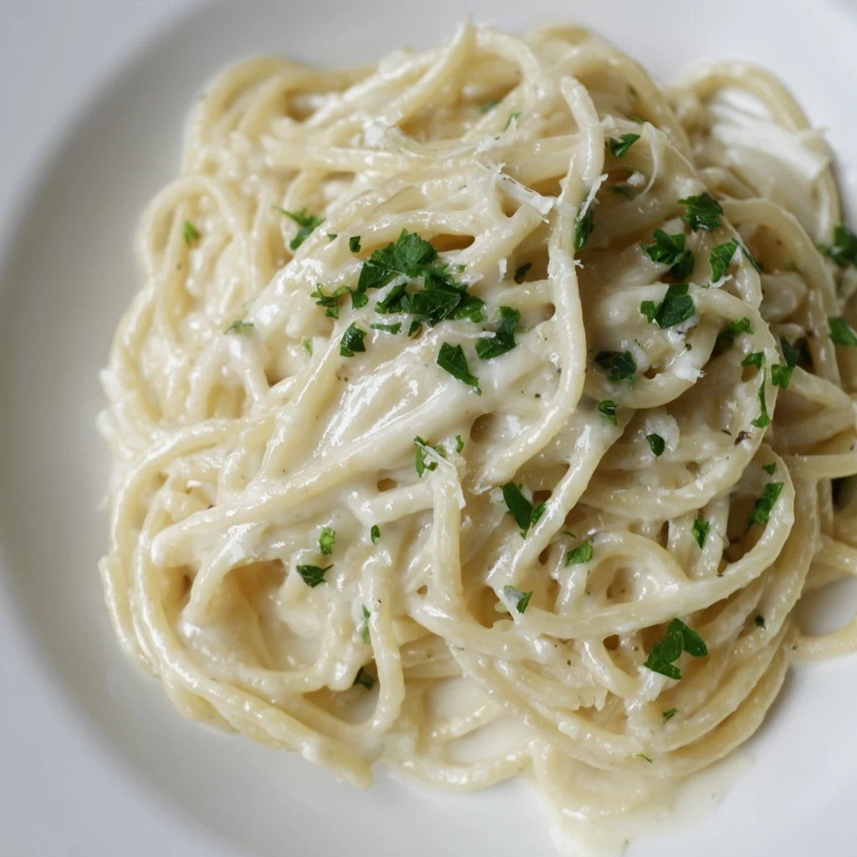 A close-up of a bowl of delicious Creamy Three-Cheese Spaghetti, garnished with fresh parsley, ready to serve.