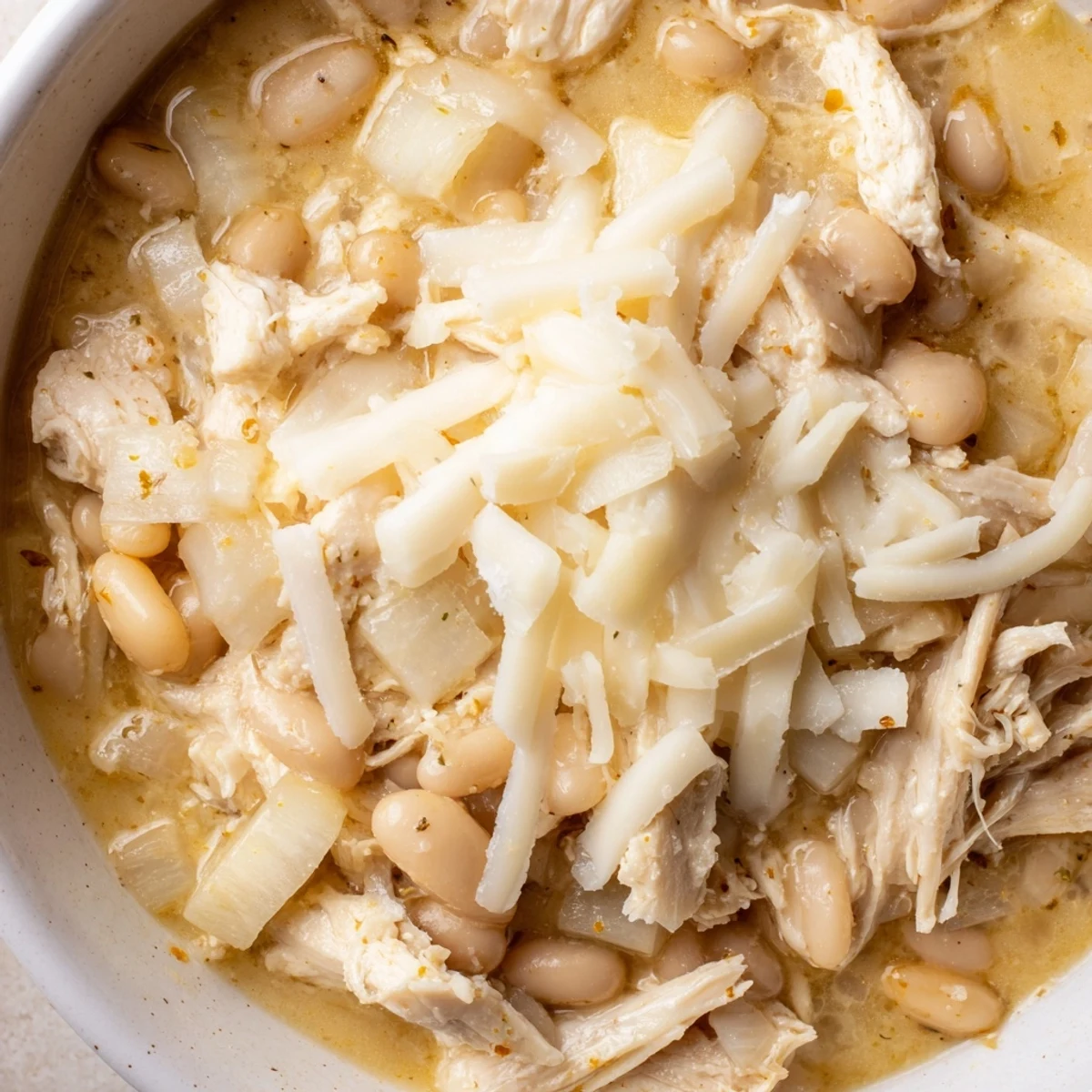 Steaming bowl of 35-Minute White Cheddar Apple Chicken Chili, featuring melted cheese and tender chicken.