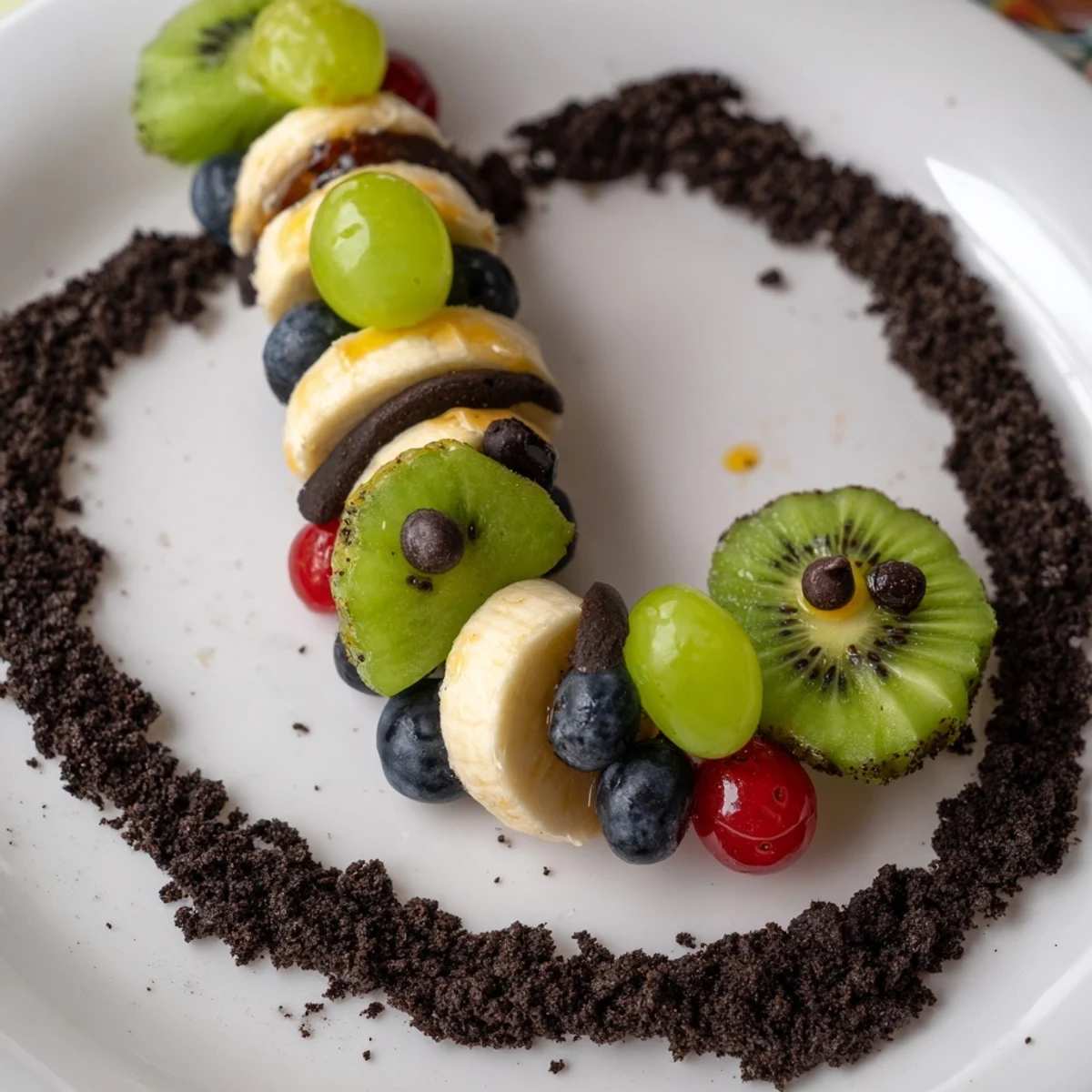 Vibrant Caterpillar Fruit Skewer Track with colorful fruit on a chocolate cookie crumb pathway for kids.