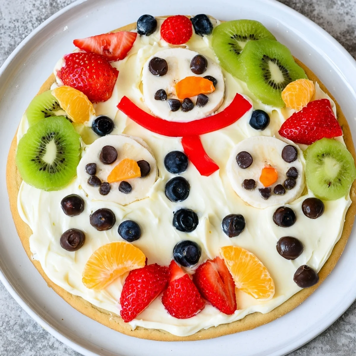 This delicious Melting Snowman Fruit Pizza dessert boasts a cheerful, colorful arrangement of fresh toppings.