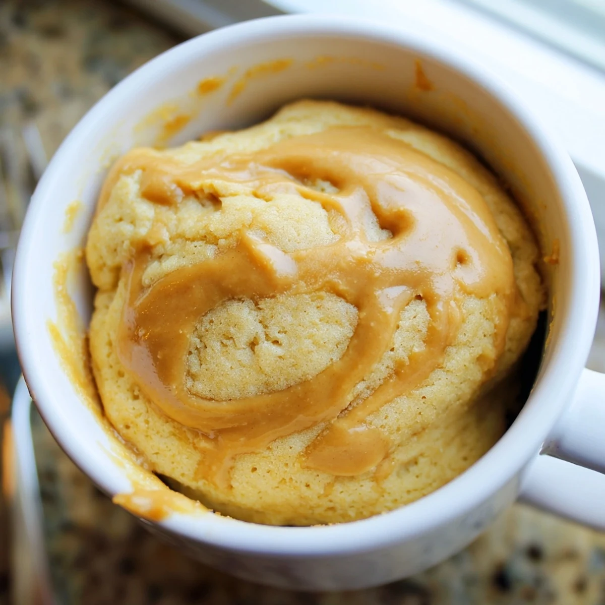 Warm, fluffy 2-Minute Peanut Butter Mug Cake topped with a few chocolate chips, ready to eat.