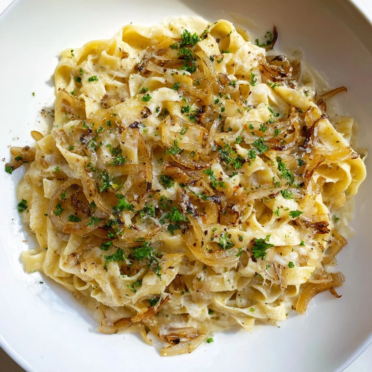 A warm bowl displays the delicious One-Pot French Onion Pasta, creamy and topped with melted Gruyère cheese.