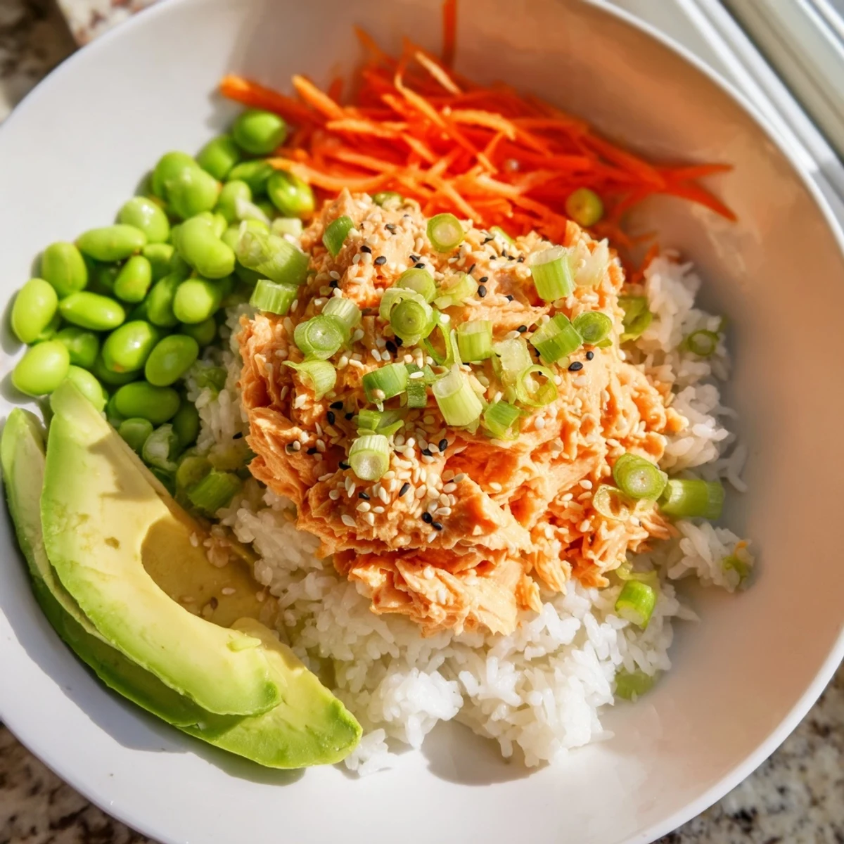 A close-up of a Spicy Canned Salmon Rice Bowl showcases creamy salmon and colorful veggies.