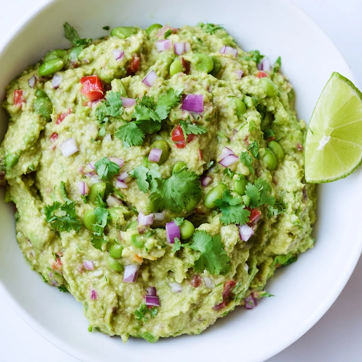 Close-up of chunky edamame guacamole, showing the creamy avocado texture and colorful vegetables.