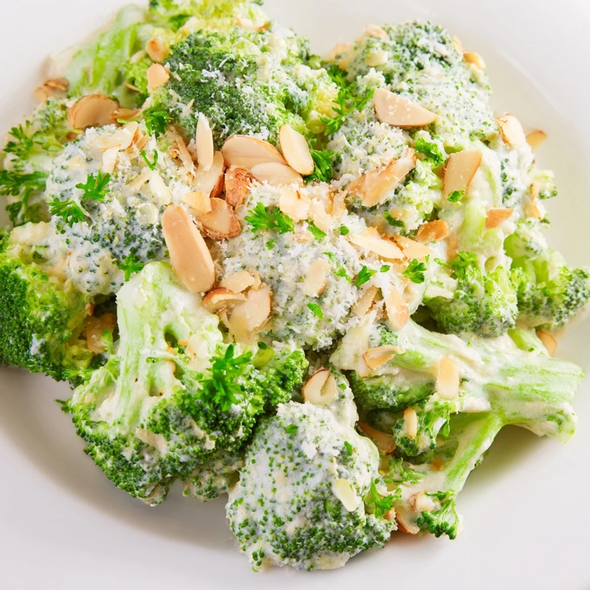 A vibrant bowl of Garlic Parmesan Broccoli Salad featuring crisp green florets, diced red onion, and creamy dressing.