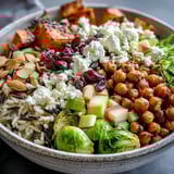 Fall Harvest Bowl featuring wild rice, crispy chickpeas, sliced celery, creamy feta, and a drizzle of dressing.