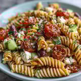 A vibrant pasta salad featuring cherry tomatoes, bell peppers, and black olives, tossed in zesty homemade Italian dressing for a picnic-ready meal.  