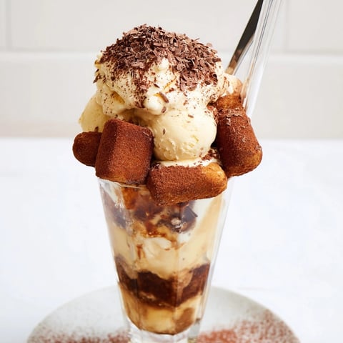 Creamy Tiramisu Float: A layered dessert in a glass, topped with cocoa and chocolate.