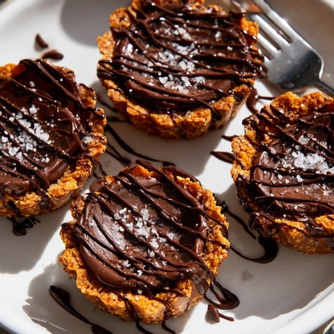 Mini pumpkin chocolate pretzel tartlets drizzled with chocolate and sprinkled with sea salt.  