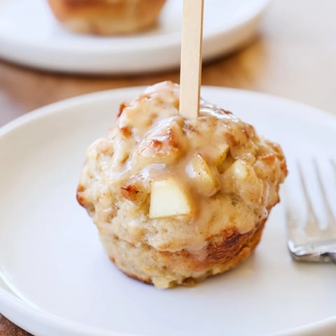 Warm Maple Bourbon Apple Cheddar Biscuit Muffin Pops drizzled with syrup on a plate.