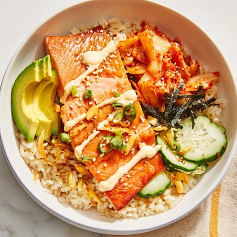 Crispy Salmon Rice Bowl topped with spicy mayo, tangy kimchi, and fresh avocado slices.  