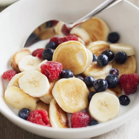 Adorable mini pancake cereal stacked in a bowl, ready to be drizzled with syrup.  