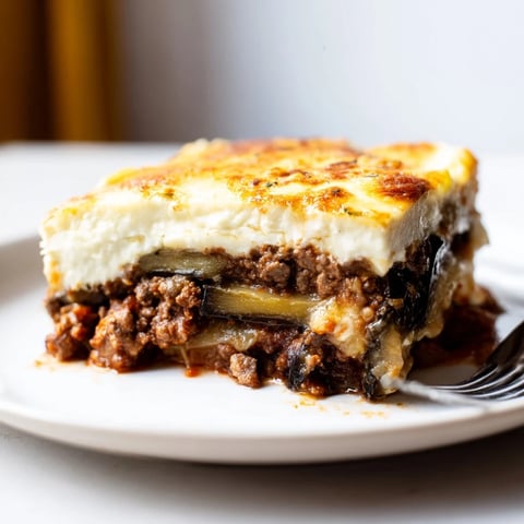 Moussaka with Beef & Eggplant served hot, layered with spiced meat and creamy sauce.  