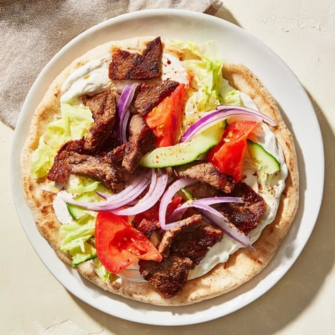 Juicy beef shawarma wraps, filled with vibrant veggies and drizzled with creamy yogurt sauce.