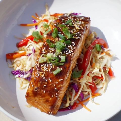Flaky teriyaki salmon glistens atop a crunchy Asian slaw in this colorful bowl.