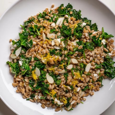 Warm Farro & Greens Pilaf with toasted almonds in a bowl, showcasing vibrant greens and earthy farro.