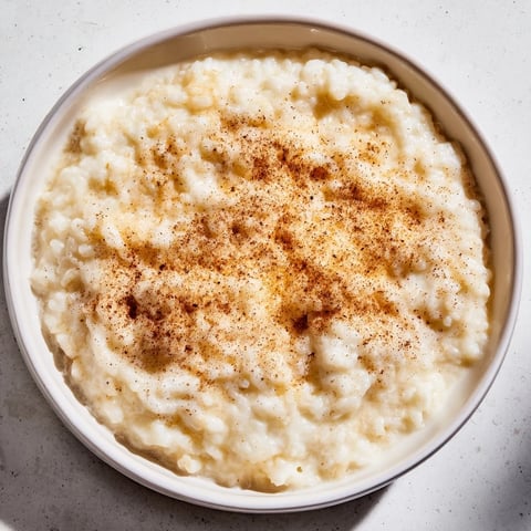 Creamy rice pudding with leftover rice, dusted with cinnamon, served warm in a bowl.