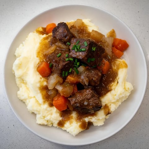 Fall Apple Cider Stew Mash served steaming hot over creamy cheddar mashed potatoes, a comforting dinner.