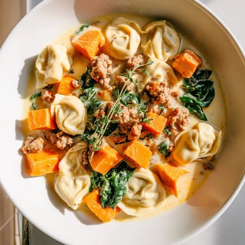 Creamy Sausage Tortellini Soup features tender sweet potatoes and vibrant spinach, a hearty meal.