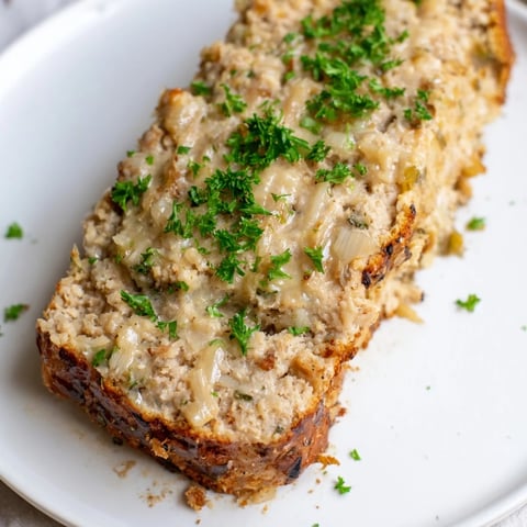 A savory, steaming slice of Juicy Garlic Parmesan Chicken Meatloaf, perfect for a hearty meal.