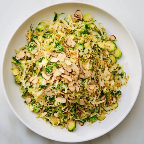 Fresh Crunchy Lemon Parmesan Brussels Sprouts Salad, dressed and ready to enjoy with toasted almonds and Parmesan.
