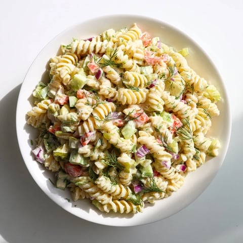 A chilled bowl of Dill Pickle Chopped Pasta Salad, featuring vibrantly colored vegetables and creamy dressing.