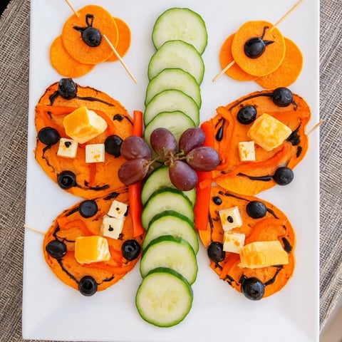 A colorful Monarch Butterfly Wings platter featuring roasted sweet potato and black olive accents.
