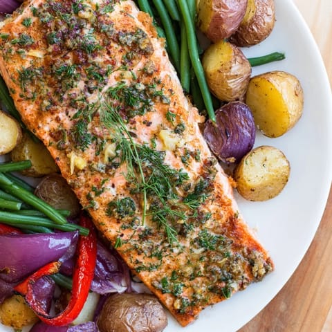 This image shows a sheet pan of cooked Lemon Herb Salmon and potatoes, garnished with fresh lemon wedges.