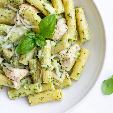 A close-up shot of Creamy Pesto Penne & Chicken with fresh basil sprinkled on top.