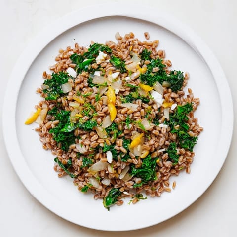 A flavorful Warm Farro & Greens Pilaf, topped with toasted almonds and fresh parsley, ready to eat.