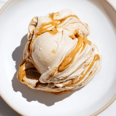 A scoop of homemade peanut butter banana ice cream drizzled with chocolate, a delicious treat.