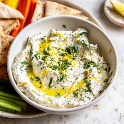Freshly made whipped feta, ready to scoop with warm pita, showcasing Greek flavors.