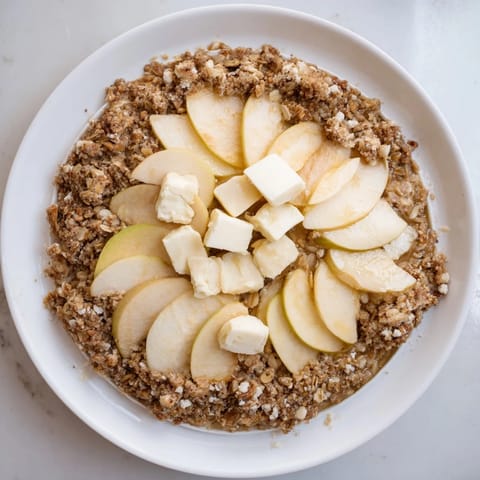 A close-up of a bubbling Best Apple Crisp, showcasing the tender apples and oat crumble texture.