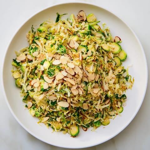 Fresh Crunchy Lemon Parmesan Brussels Sprouts Salad, dressed and ready to enjoy with toasted almonds and Parmesan.