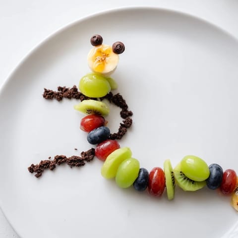 Playful Caterpillar Fruit Skewer Track: Sweet strawberry and grape caterpillars crawling on a cookie crumb trail.