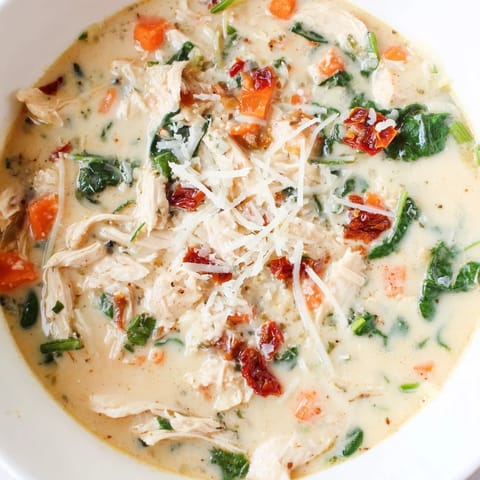Creamy Tuscan Chicken Soup simmering in a pot with shredded chicken and herbs.  