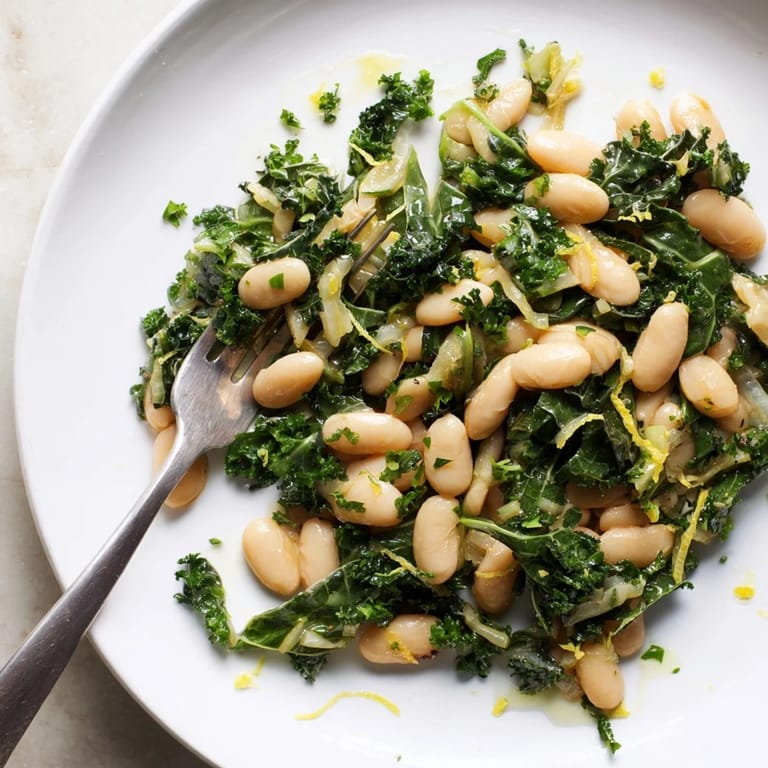 Close-up of vibrant Garlicky Beans with Winter Greens, with fresh herbs and a drizzle of olive oil.