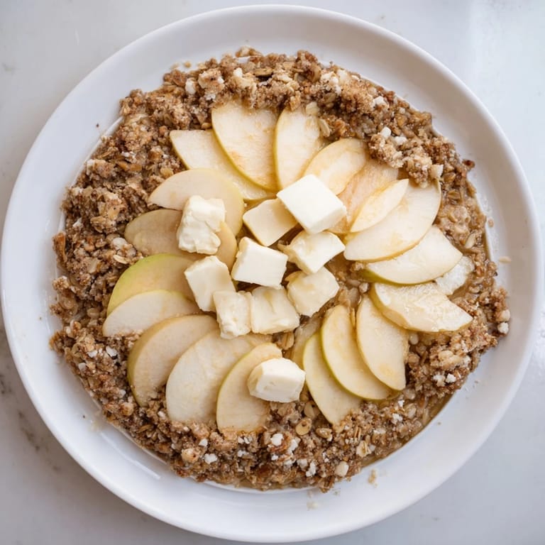 A close-up of a bubbling Best Apple Crisp, showcasing the tender apples and oat crumble texture.