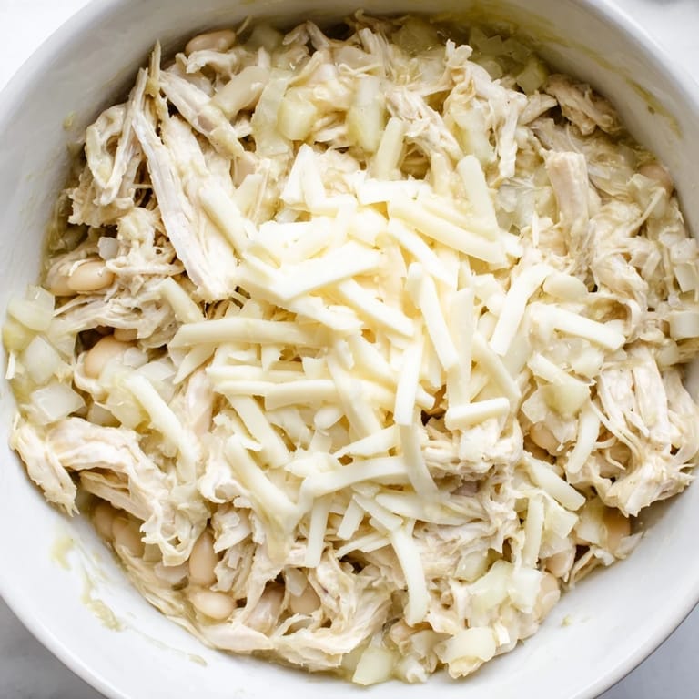 A comforting close-up of hearty 35-Minute White Cheddar Apple Chicken Chili with visible white beans and spices.