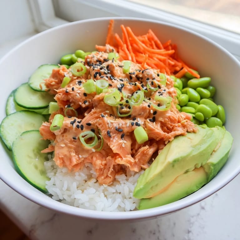 This flavorful Spicy Canned Salmon Rice Bowl features sesame seeds and fresh scallions served atop fluffy rice.