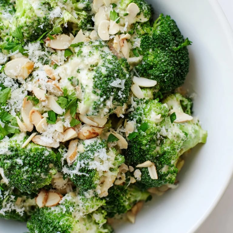 Garlic Parmesan Broccoli Salad with crunchy broccoli florets and creamy sauce, served chilled with optional cherry tomatoes.