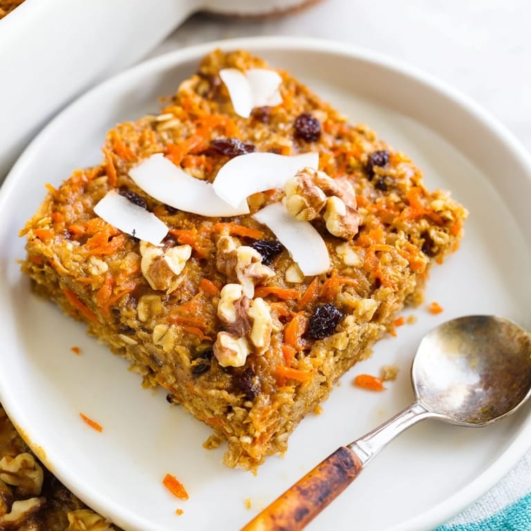 A slice of wholesome Carrot Cake Baked Oatmeal reveals tender carrots, walnuts, and raisins nestled in hearty rolled oats.  