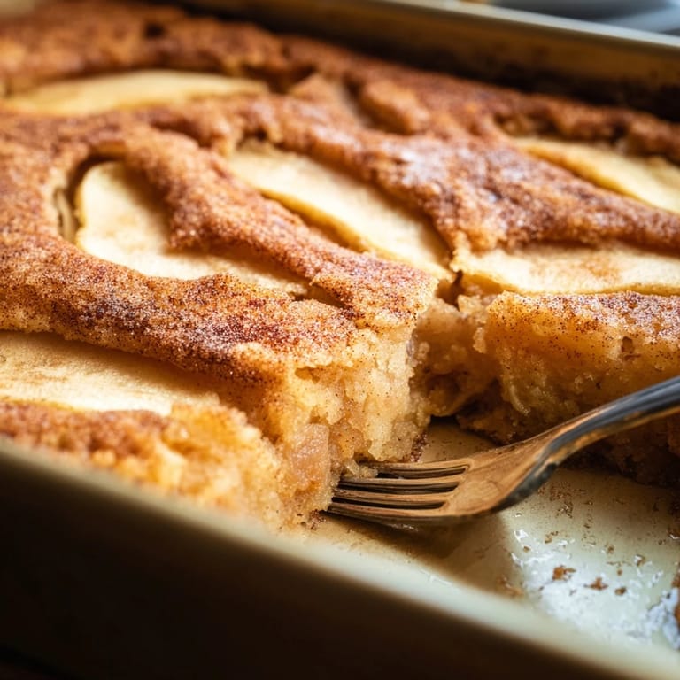A rustic Baked Apple Cake topped with cinnamon sugar, ready to be enjoyed for a comforting brunch or sweet snack.