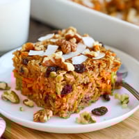 Golden-brown Carrot Cake Baked Oatmeal fresh from the oven, topped with a swirl of maple syrup and creamy Greek yogurt.  
