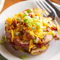 Crispy smashed green onion potato bombs topped with melted cheese and fresh herbs.  