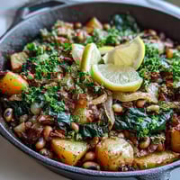 A close-up of the hearty Black-Eyed Pea Skillet Dinner, featuring golden potatoes, tender peas, and wilted spinach in a seasoned cast iron pan, ready to serve.  