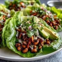 Fresh black-eyed pea filling with diced red bell pepper and cilantro, spooned into crisp butter lettuce leaves for a vibrant, gluten-free appetizer.